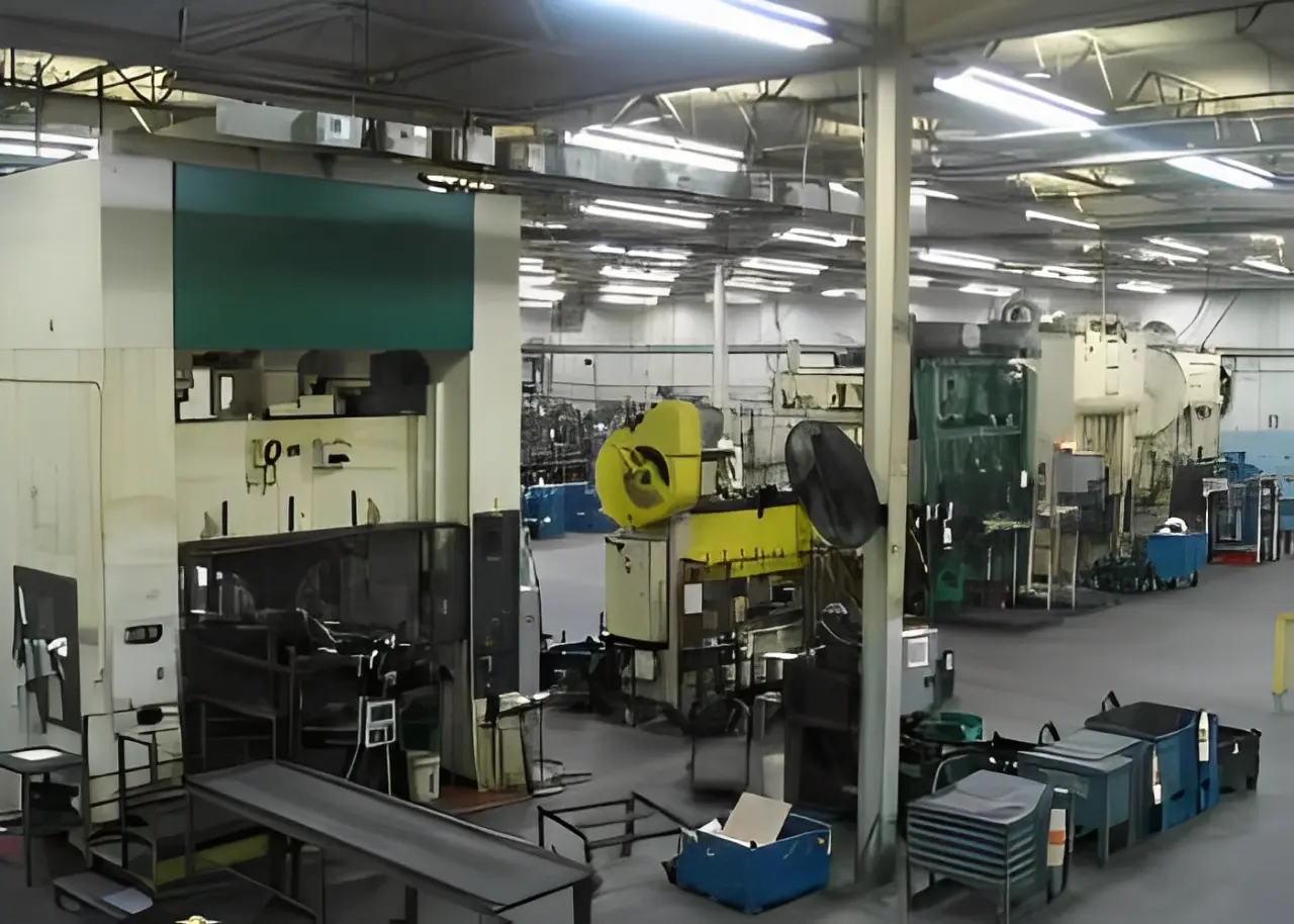 Interior of a factory with industrial machinery, including presses and fabrication equipment, scattered across a spacious, well-lit floor.